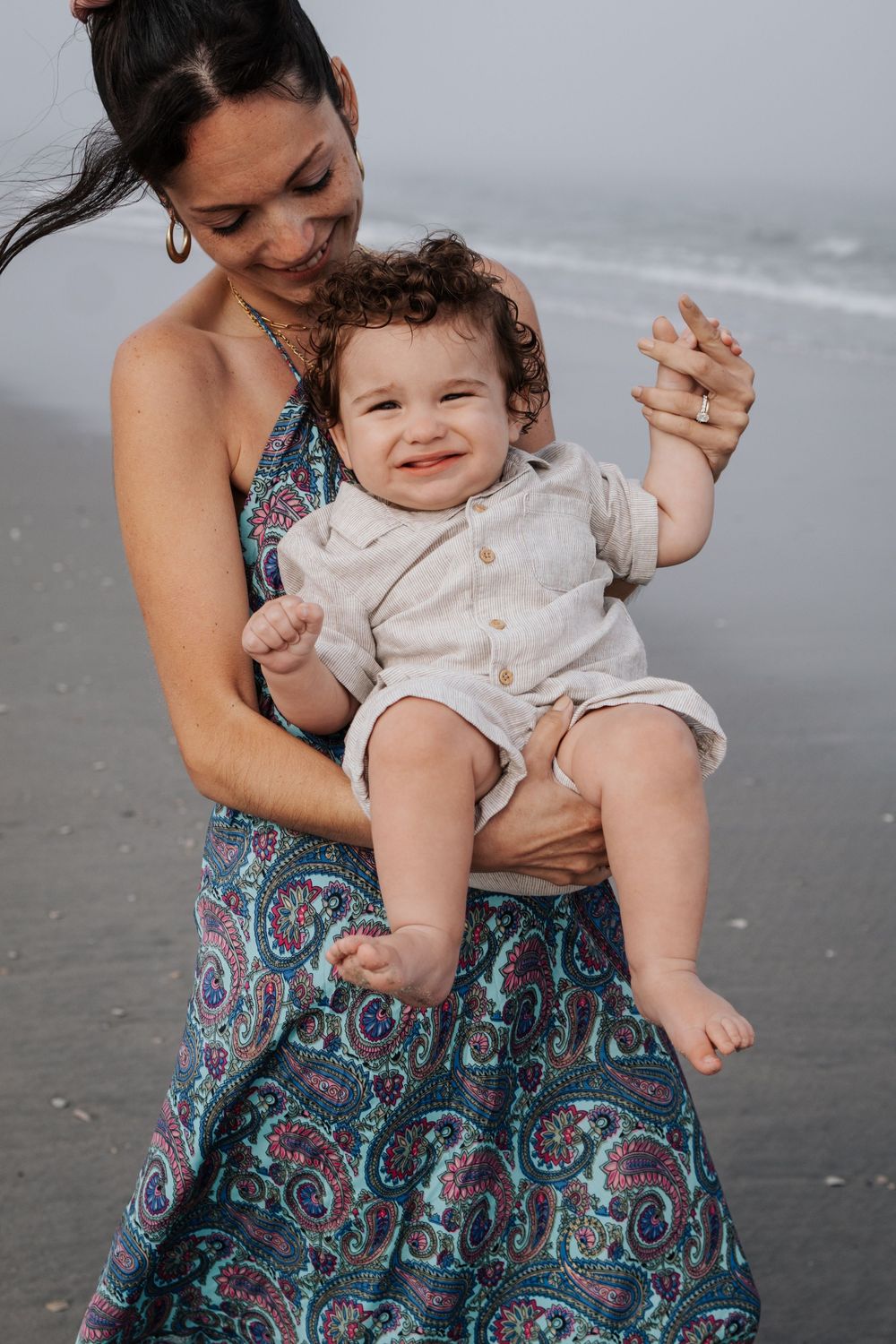 A playful beach moment with a small child wearing white.