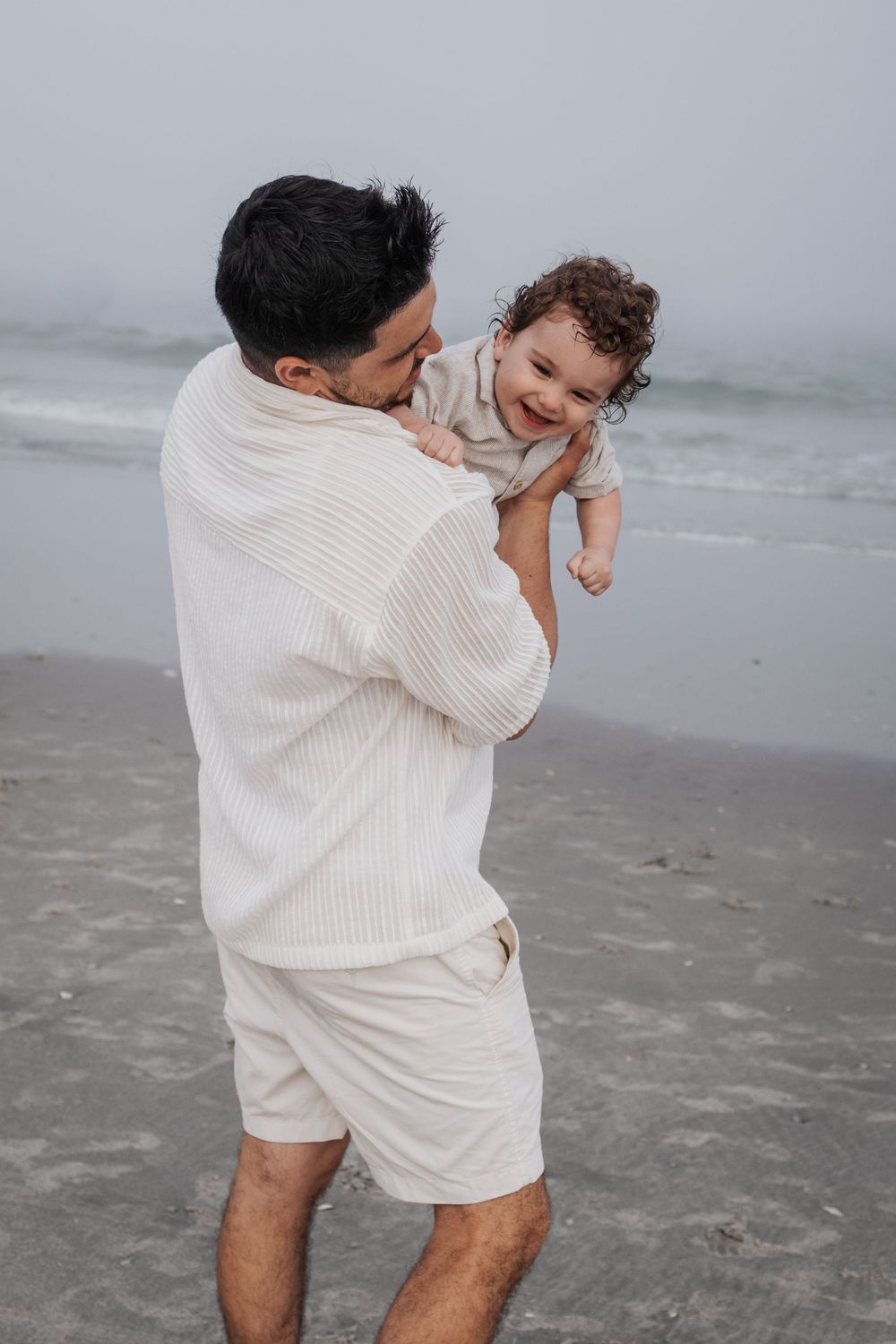 A tender moment between parent and child playing on a misty beach.