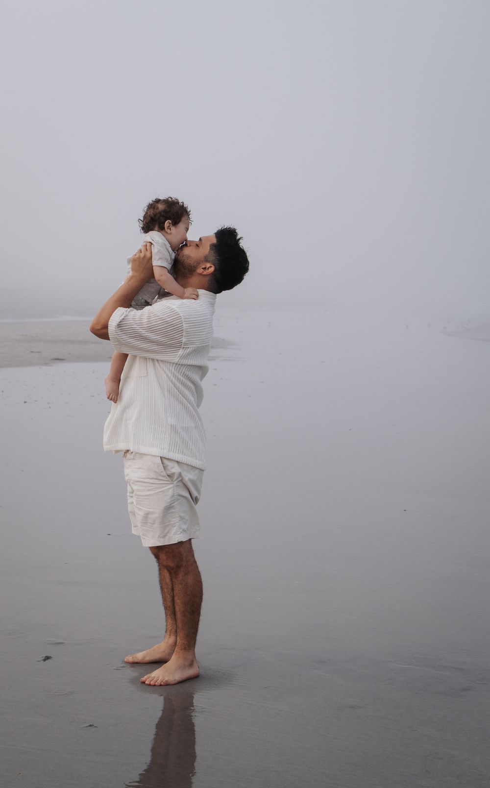 A touching moment between parent and child embracing on a foggy shoreline.