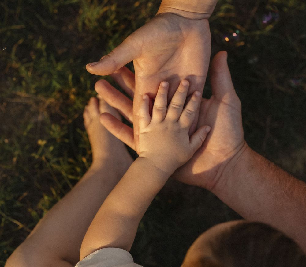 Close-up of hands joining together in warm sunset light.