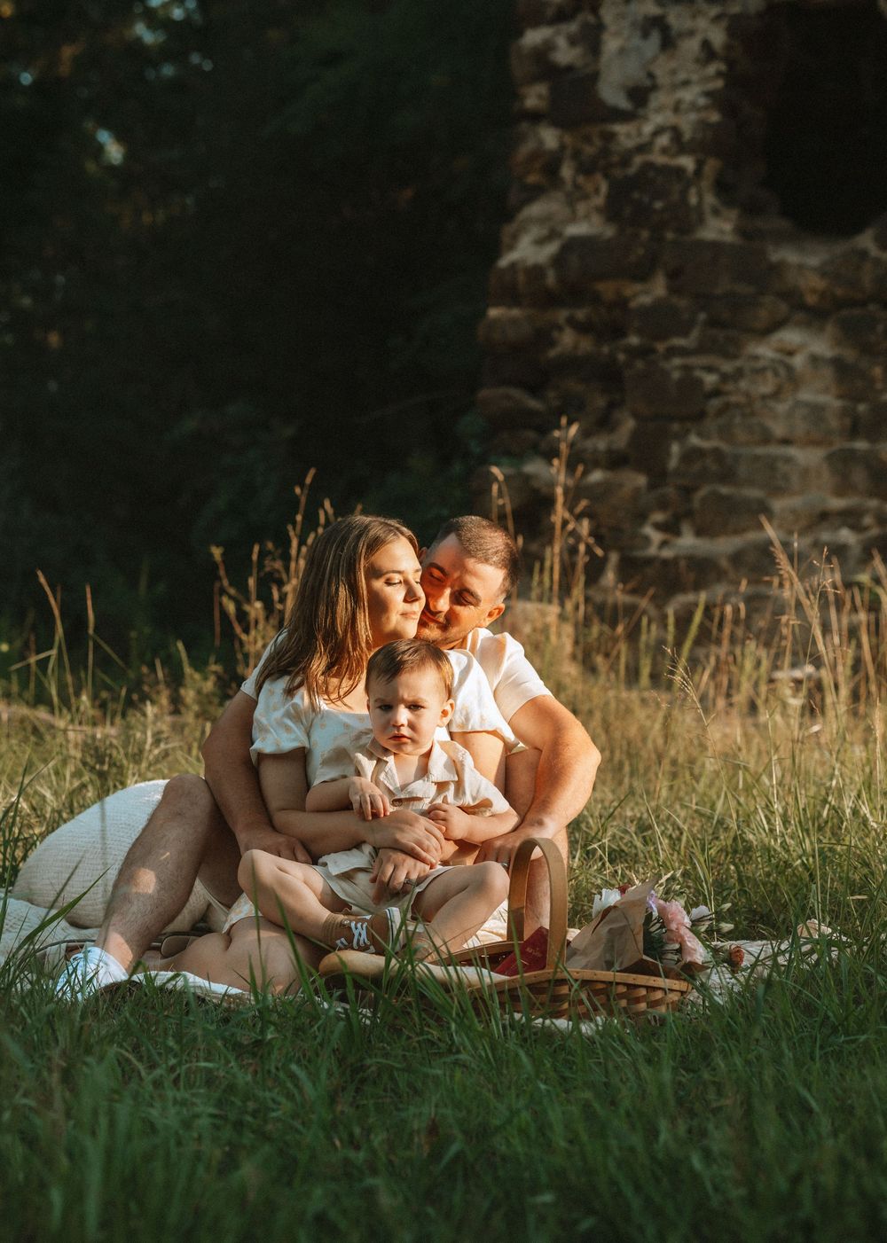 Family enjoying a tender moment together while lying in grass during golden hour.