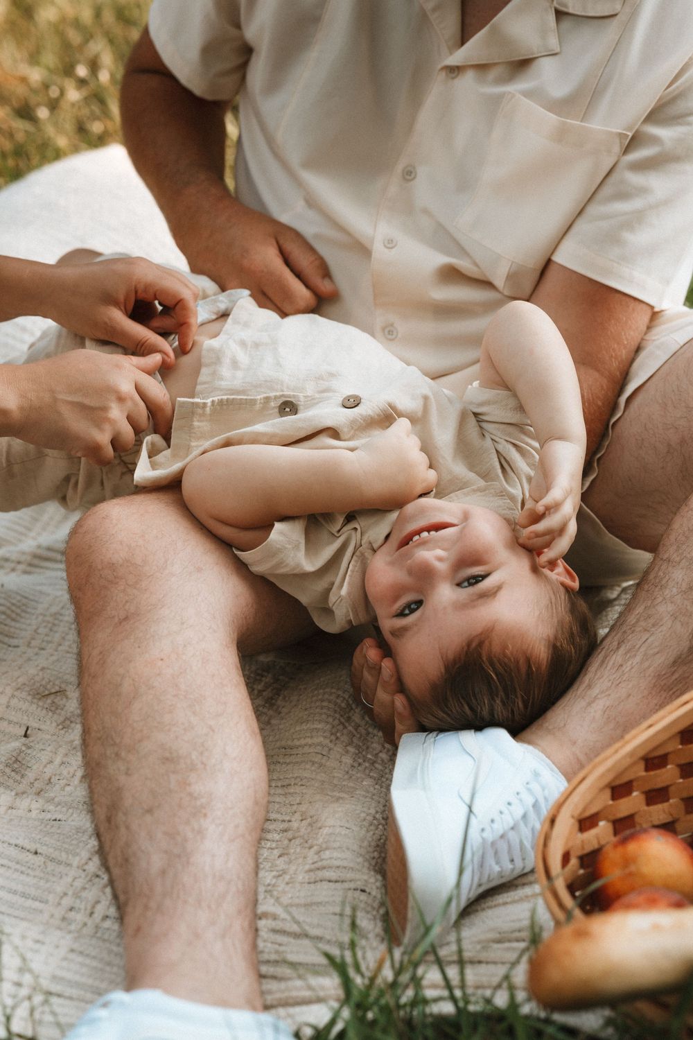 Intimate family moment captured on a picnic blanket outdoors.