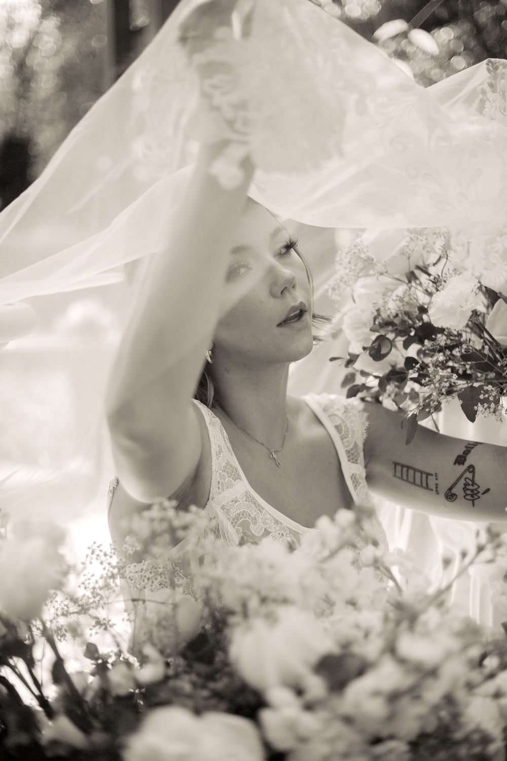 Ethereal bridal portrait in black and white with flowing veil and bouquet captured in soft dreamy lighting.
