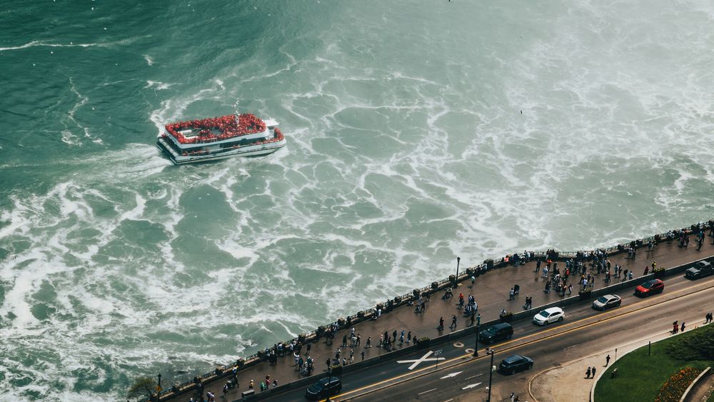 Aerial view of tourist boats navigating through the choppy waters near Niagara Falls.