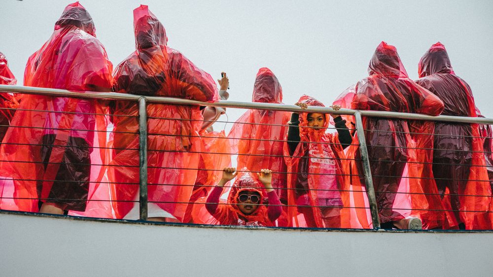 A line of red-clad figures standing against a bright background.