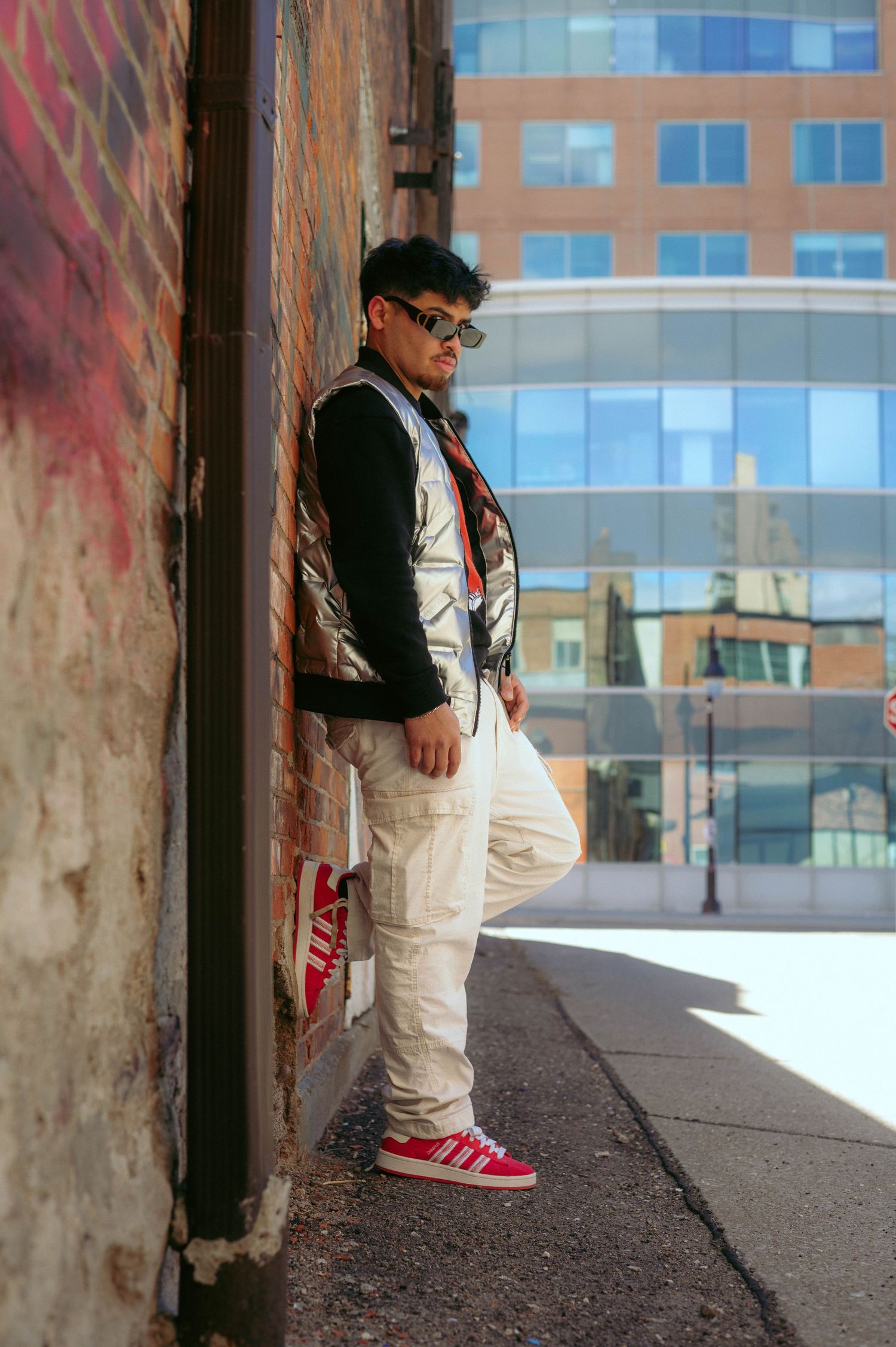 Urban street photography showing white outfit against graffiti wall and city buildings.