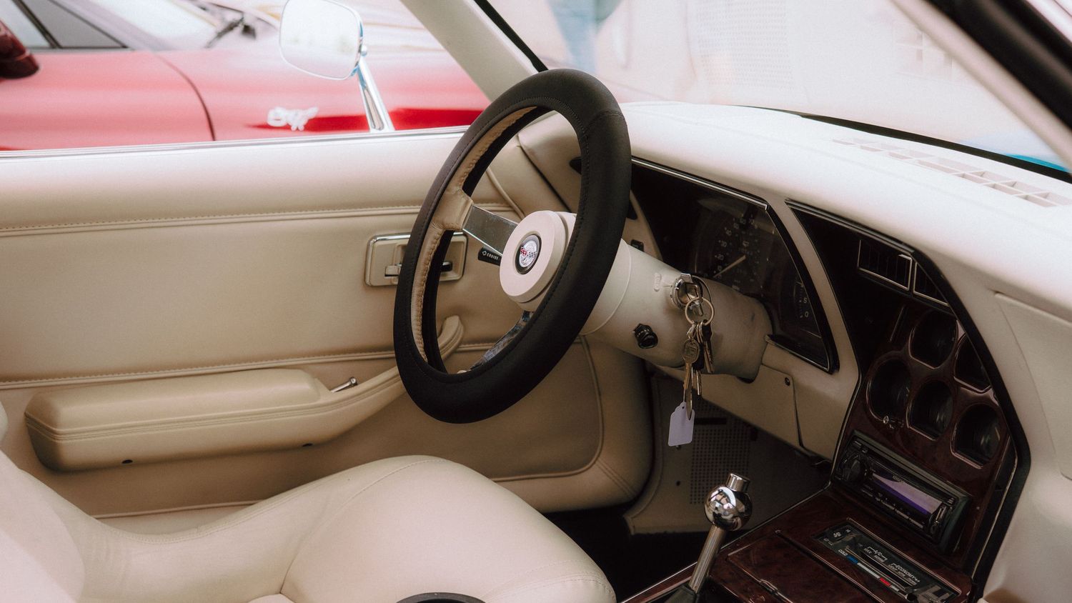 Interior dashboard and steering wheel view of a classic car in beige.
