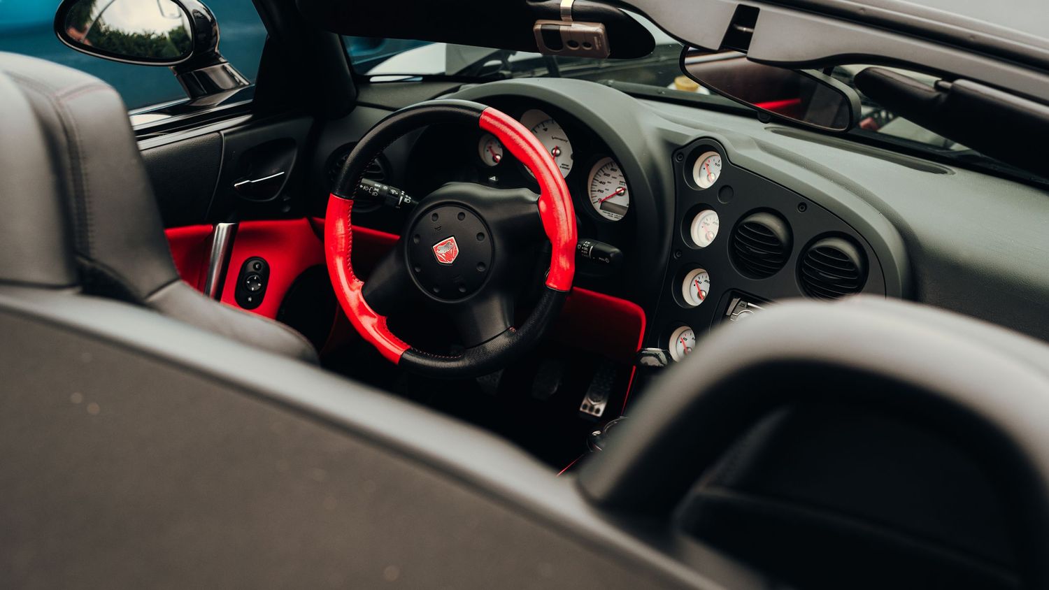Modern sports car interior featuring red accents and performance gauges.