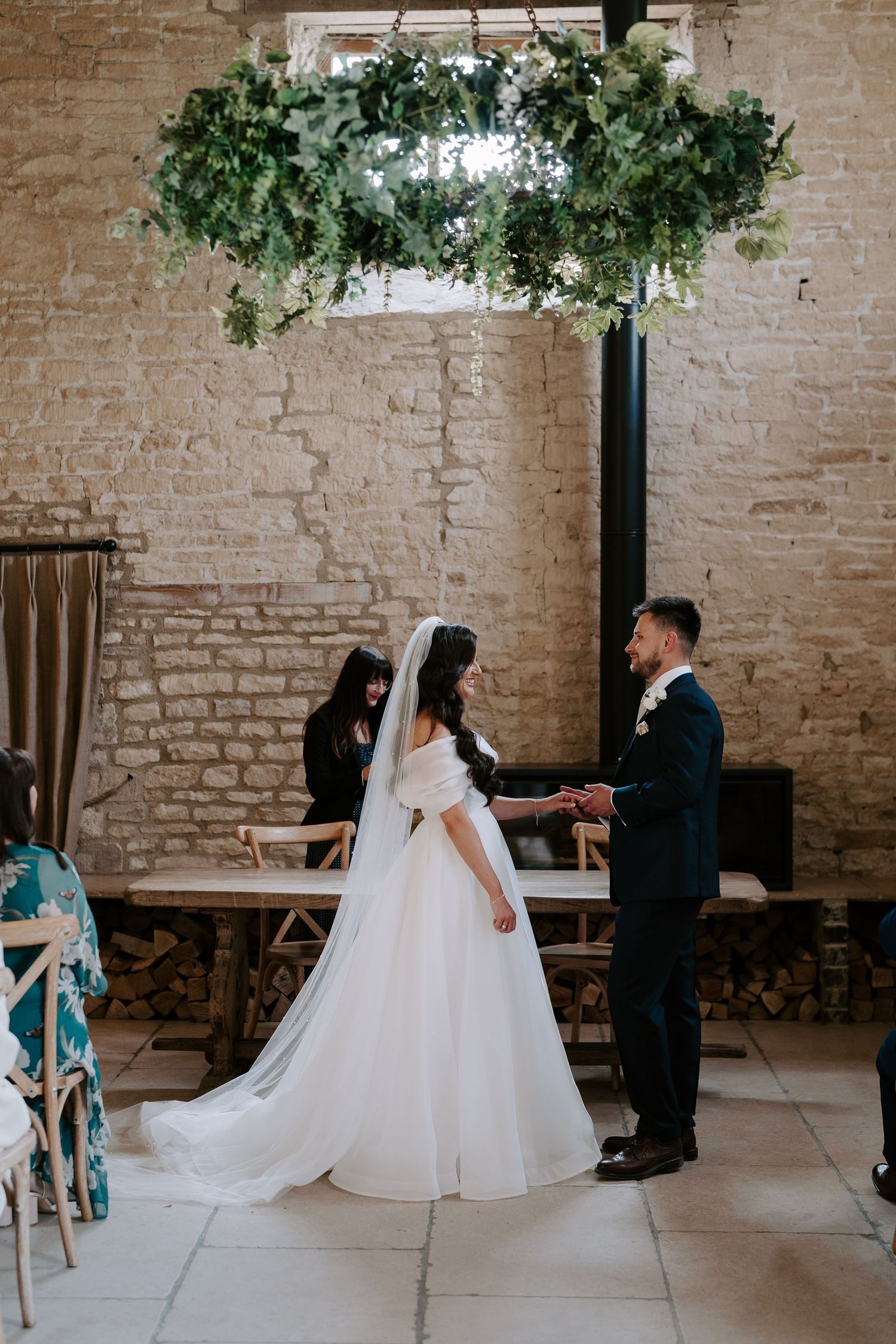 bride and groom exchanging rings during wedding ceremony at yardspace old gore in cirencester