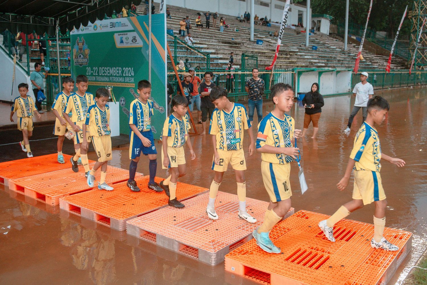 Students participate in a physical education activity using orange and white platforms in a school gymnasium.