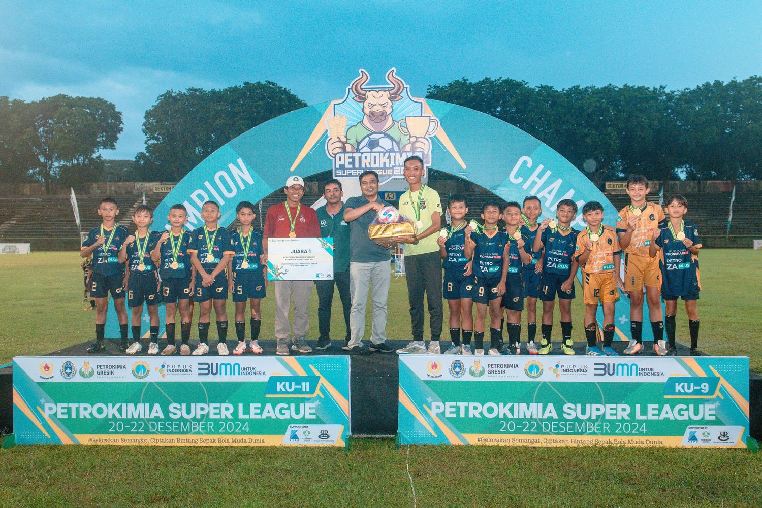 Soccer team stands on podium with awards during Petrokimia Super League championship presentation.