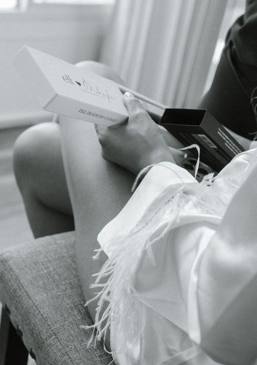 Black and white image of wrapped gifts and ribbons on grey furniture.