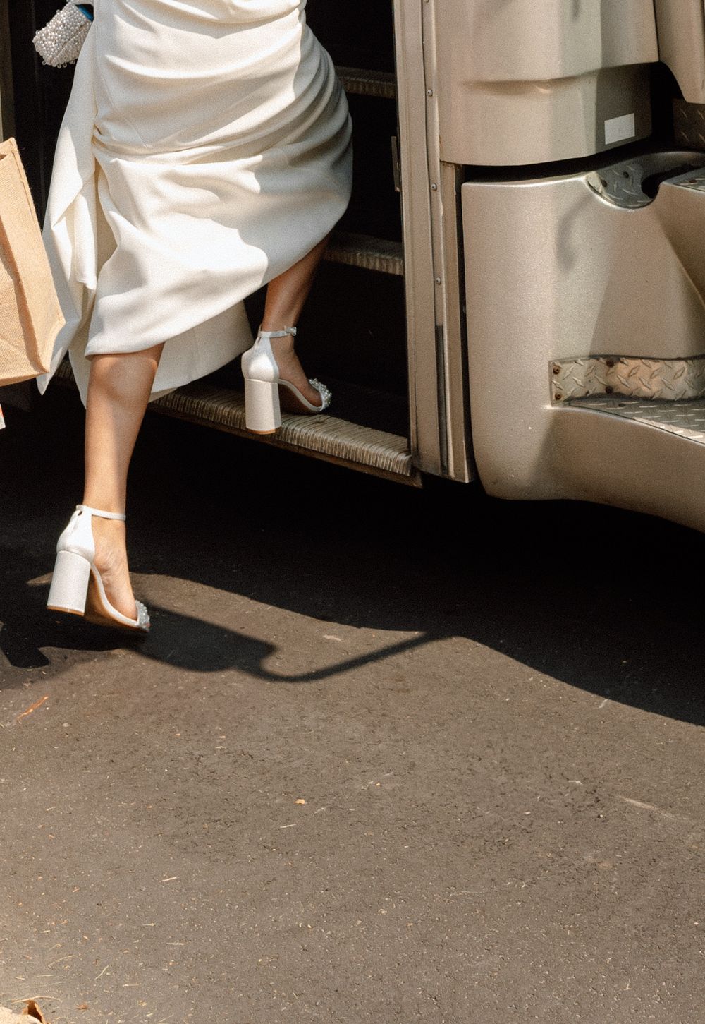 Close-up of white dress and heels against a dark floor.