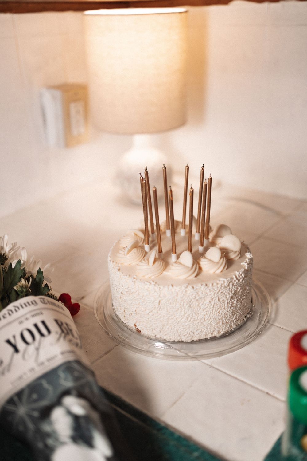 White frosted cake with wooden decorative sticks arranged on top on a clear glass cake stand.