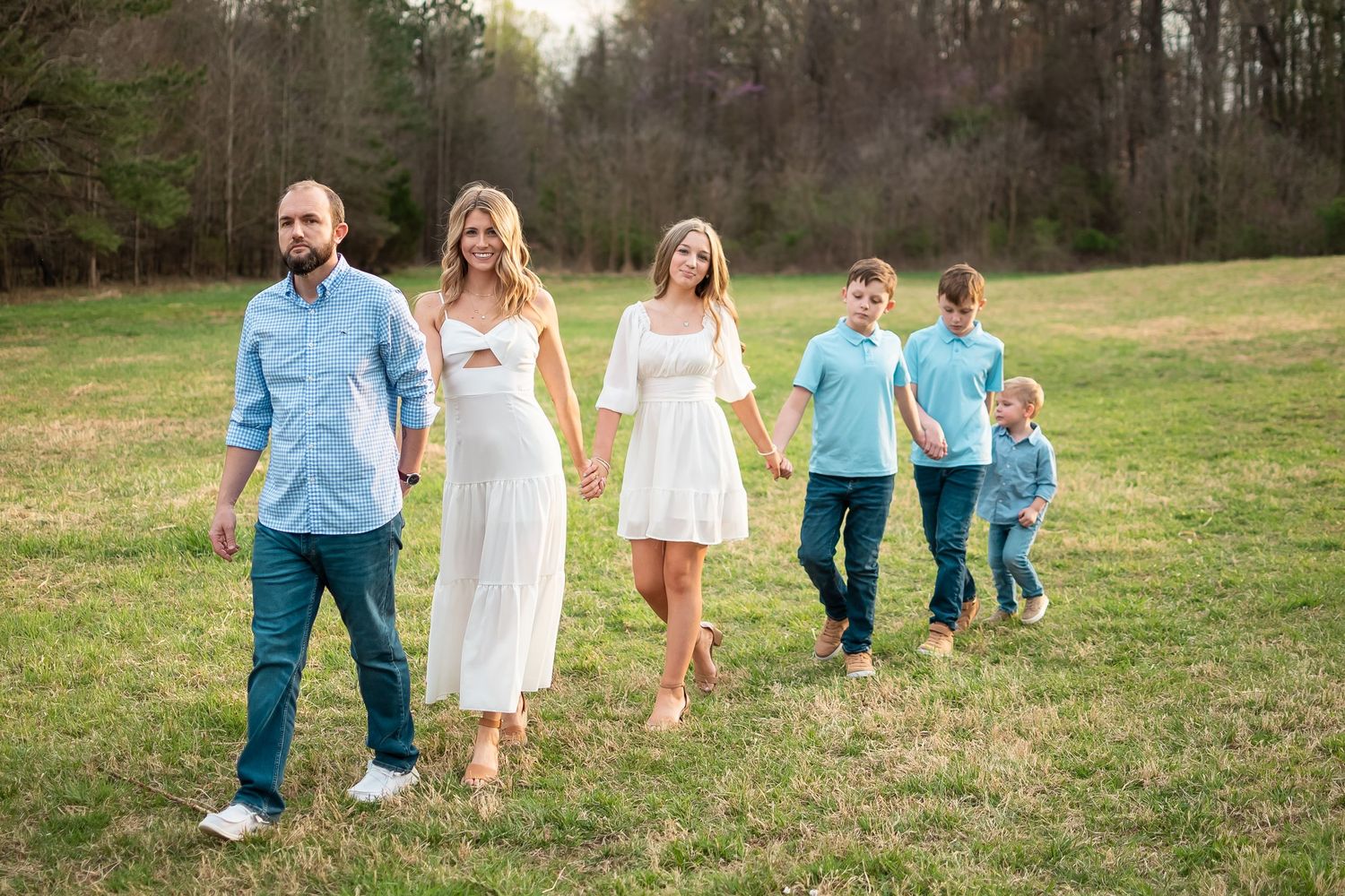 family walking across grass field for a family photo session