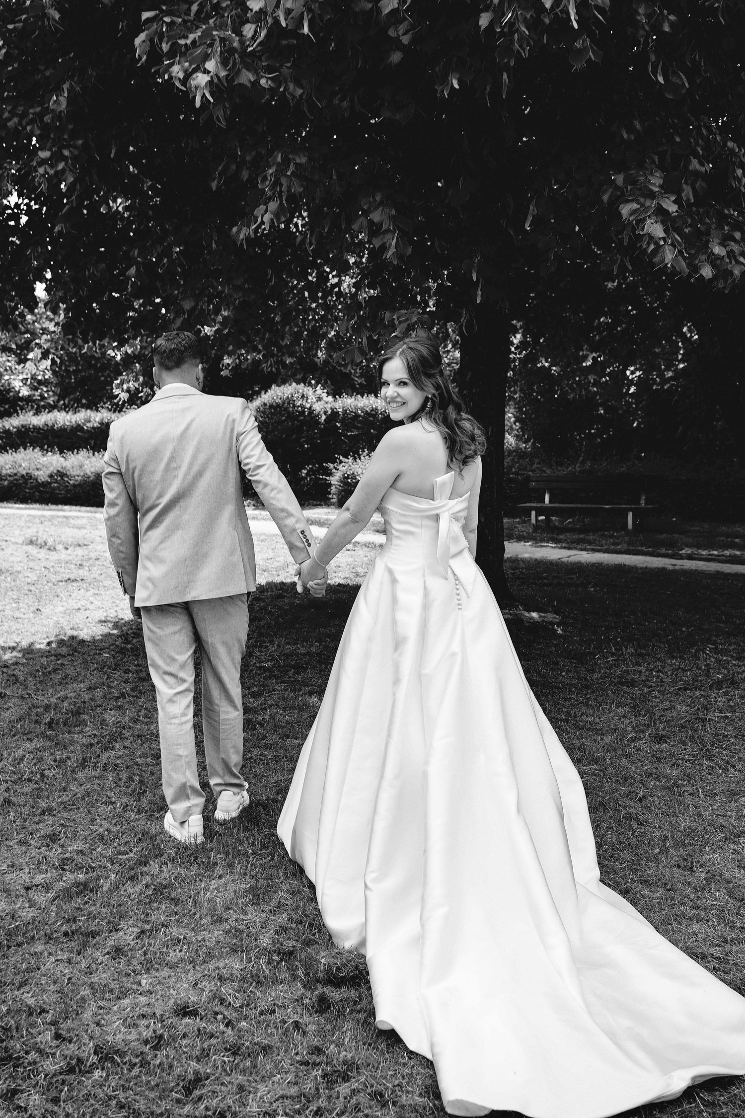 Romantic black and white photo of a couple walking through a wooded path.