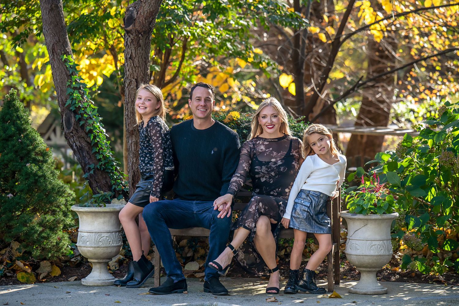 Group portrait on stone benches in a lush garden setting with autumn foliage in the background.
