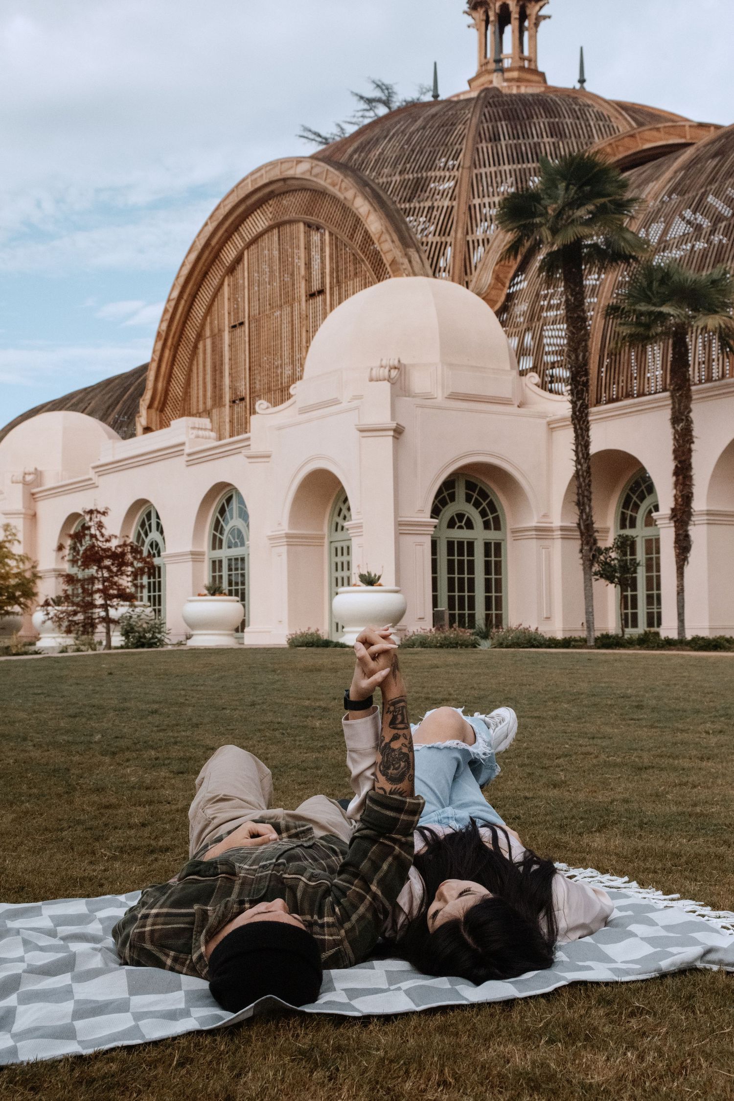 Fiancée's in Balboa Park San Diego CA, laying on blanket in front of Botanic Gardens building.