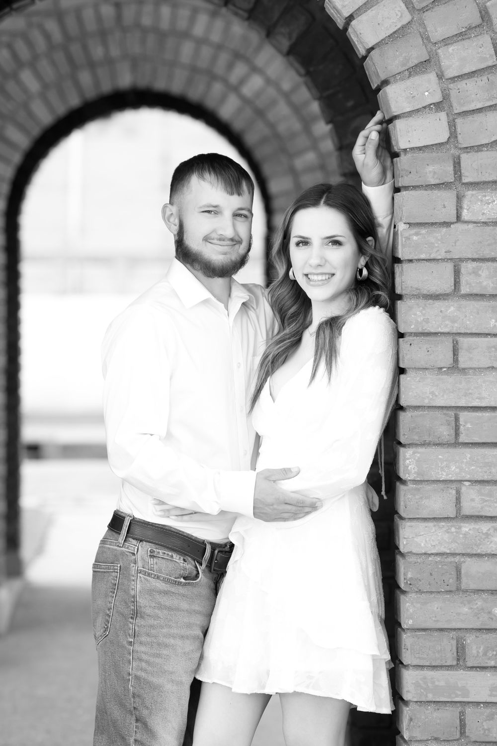 Romantic engagement photos taken under brick archways in black and white style.