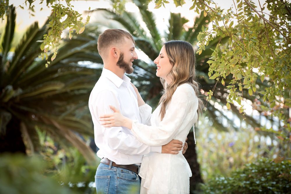 Romantic couple photos taken outdoors with lush greenery and palm trees in background.