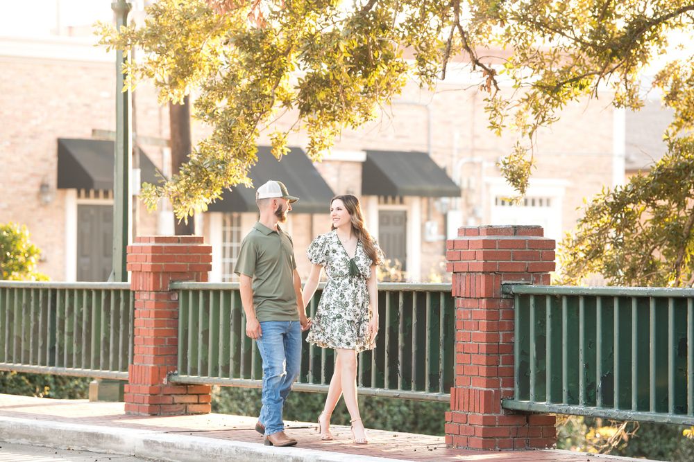 A couple walks together on a brick-lined path under golden autumn trees.