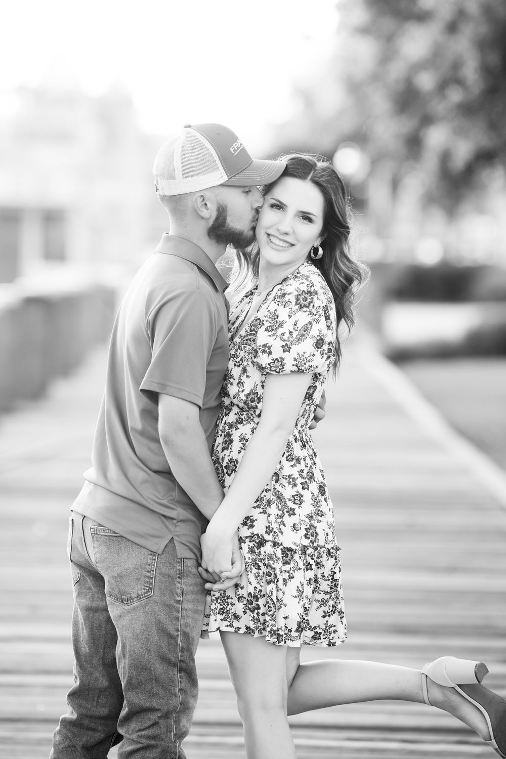 A black and white romantic portrait of a couple sharing an intimate moment outdoors.