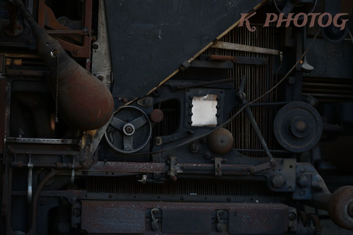A priceless antique printing press sits abandoned behind a broken out window, for some reason.