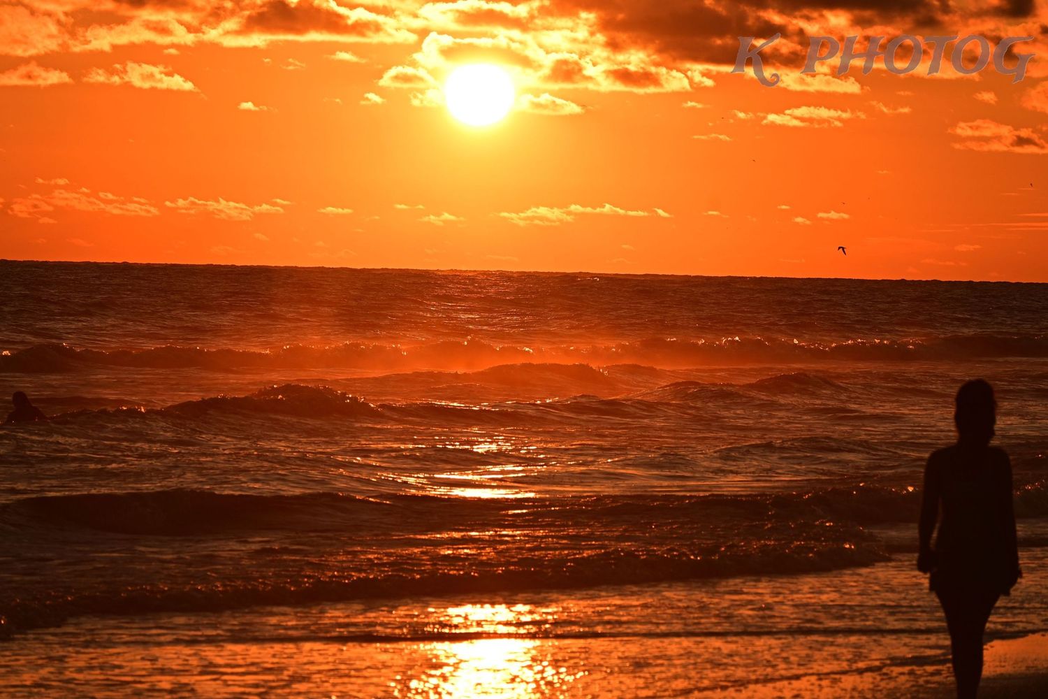 A beach sunset with a figure walking