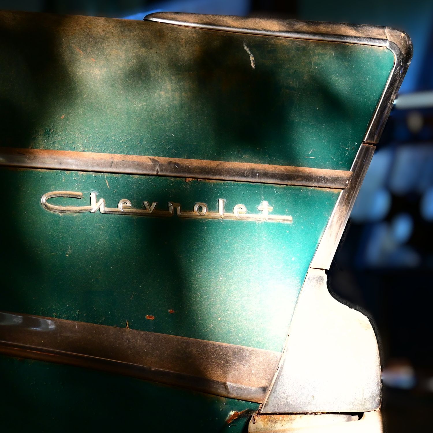 The back left tail fin of an aqua blue 1957 Chevy.