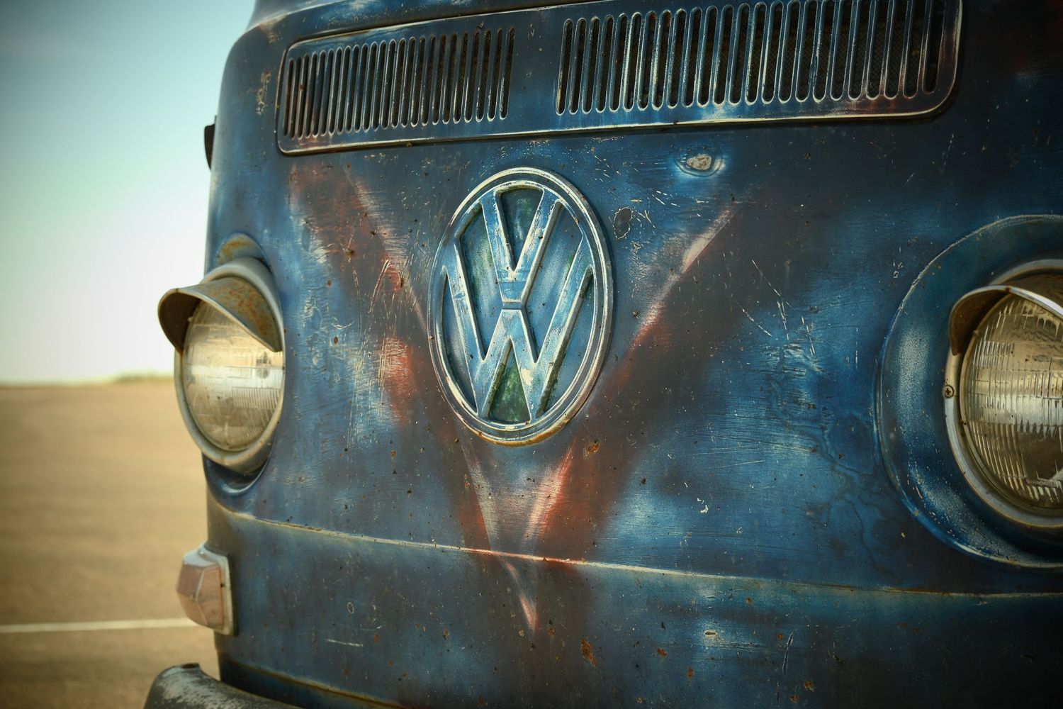 The front grill of an old, weathered blue VW van.