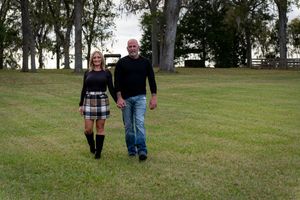 Two people walking together on a grassy lawn in a park setting.