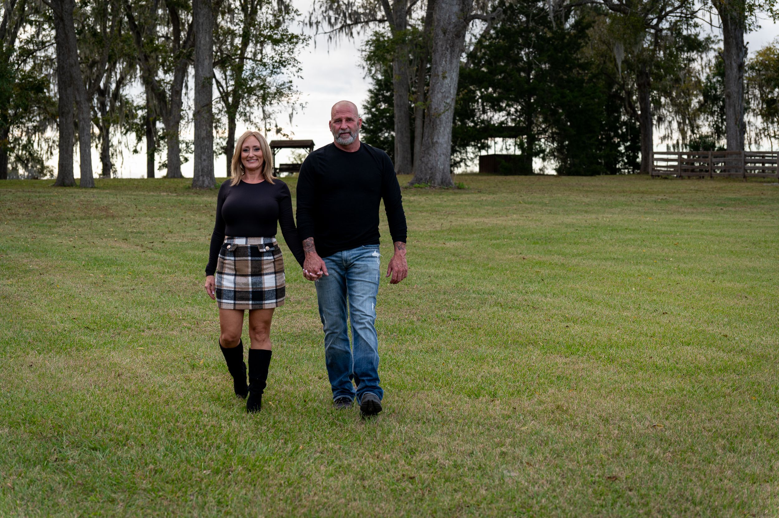 Two people walking together on a grassy lawn in a park setting.