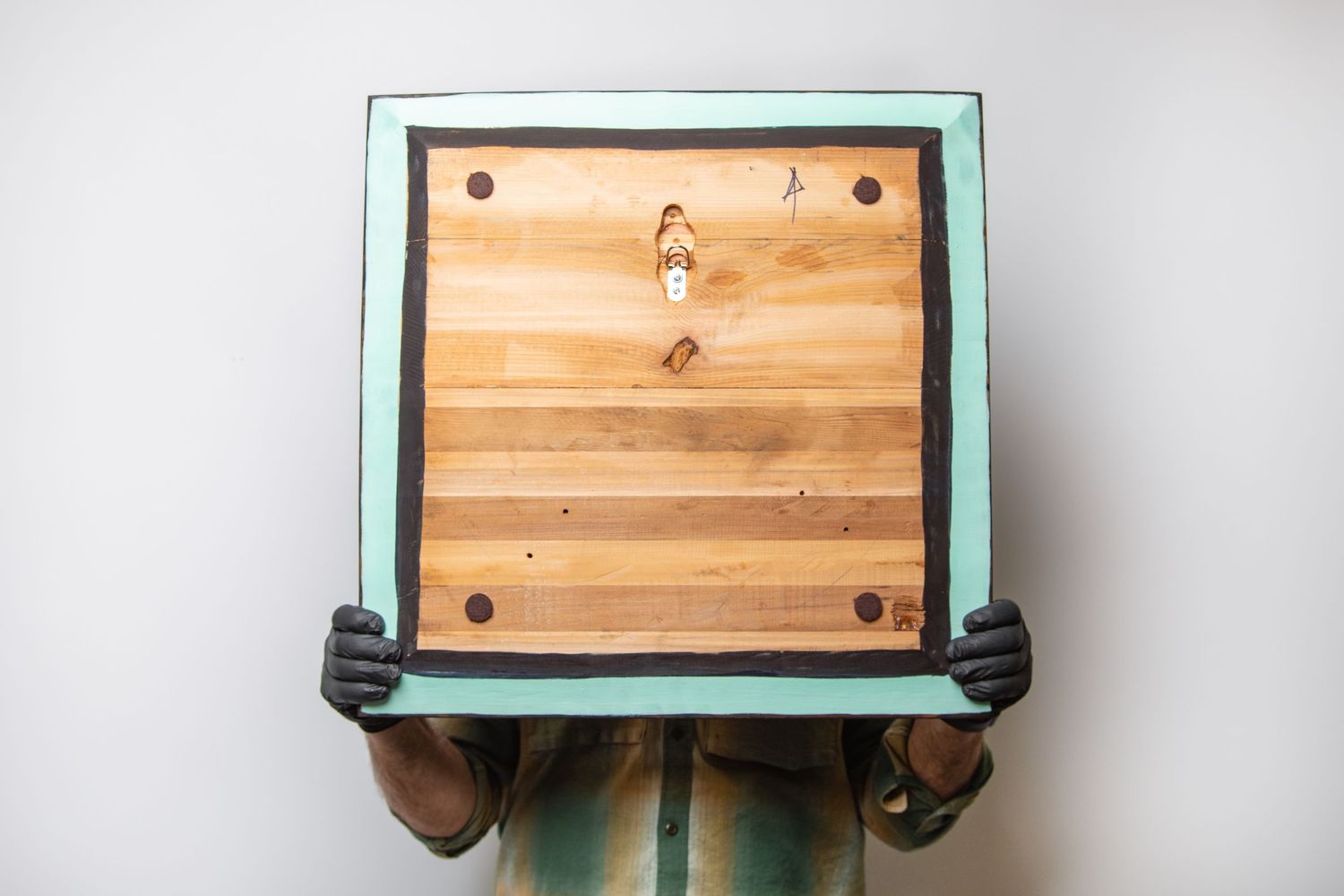 Man holding artwork backwards to show hanging hardware.
