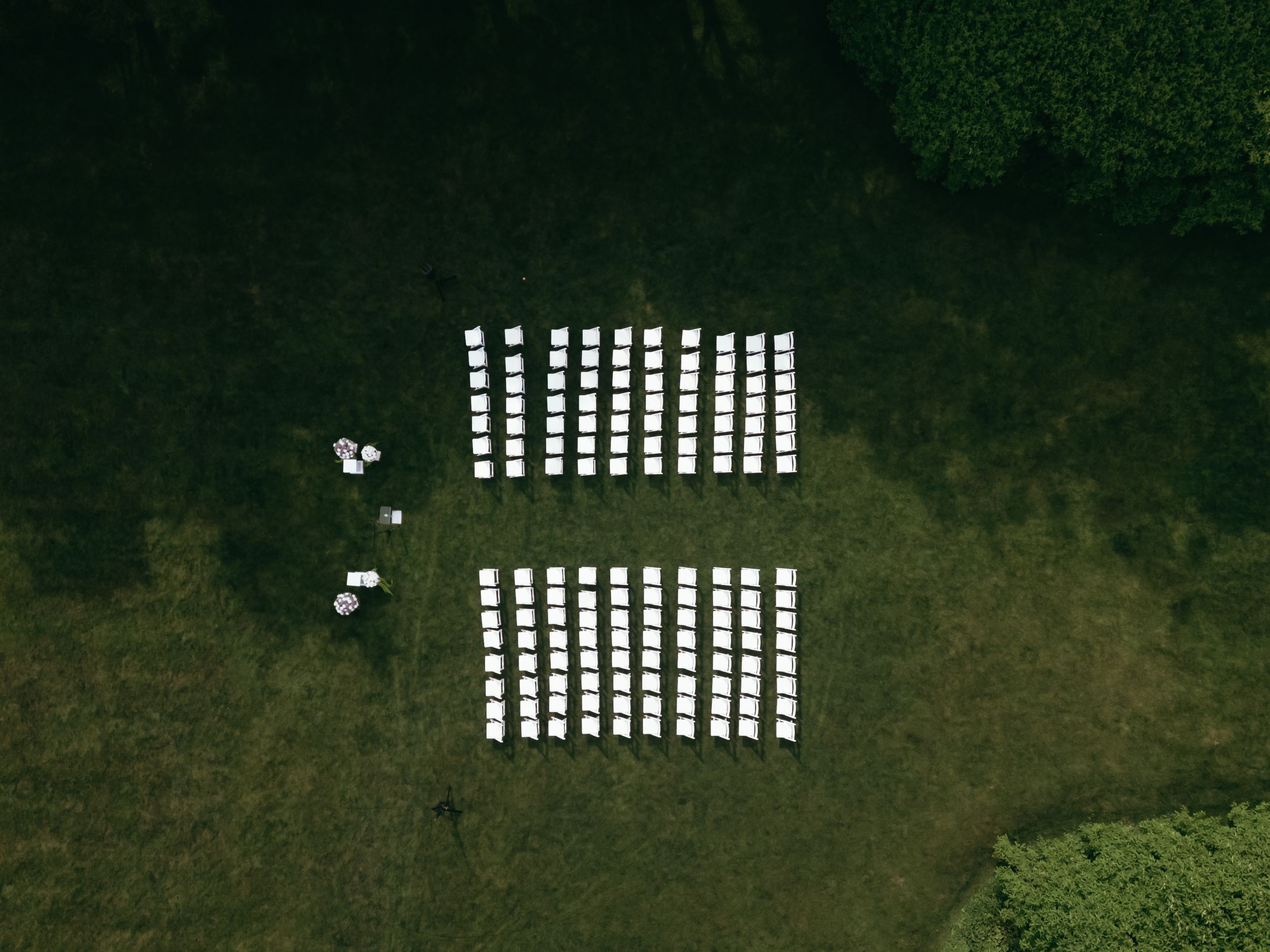 Aerial view of white rectangular markers arranged in rows on a green grassy field.