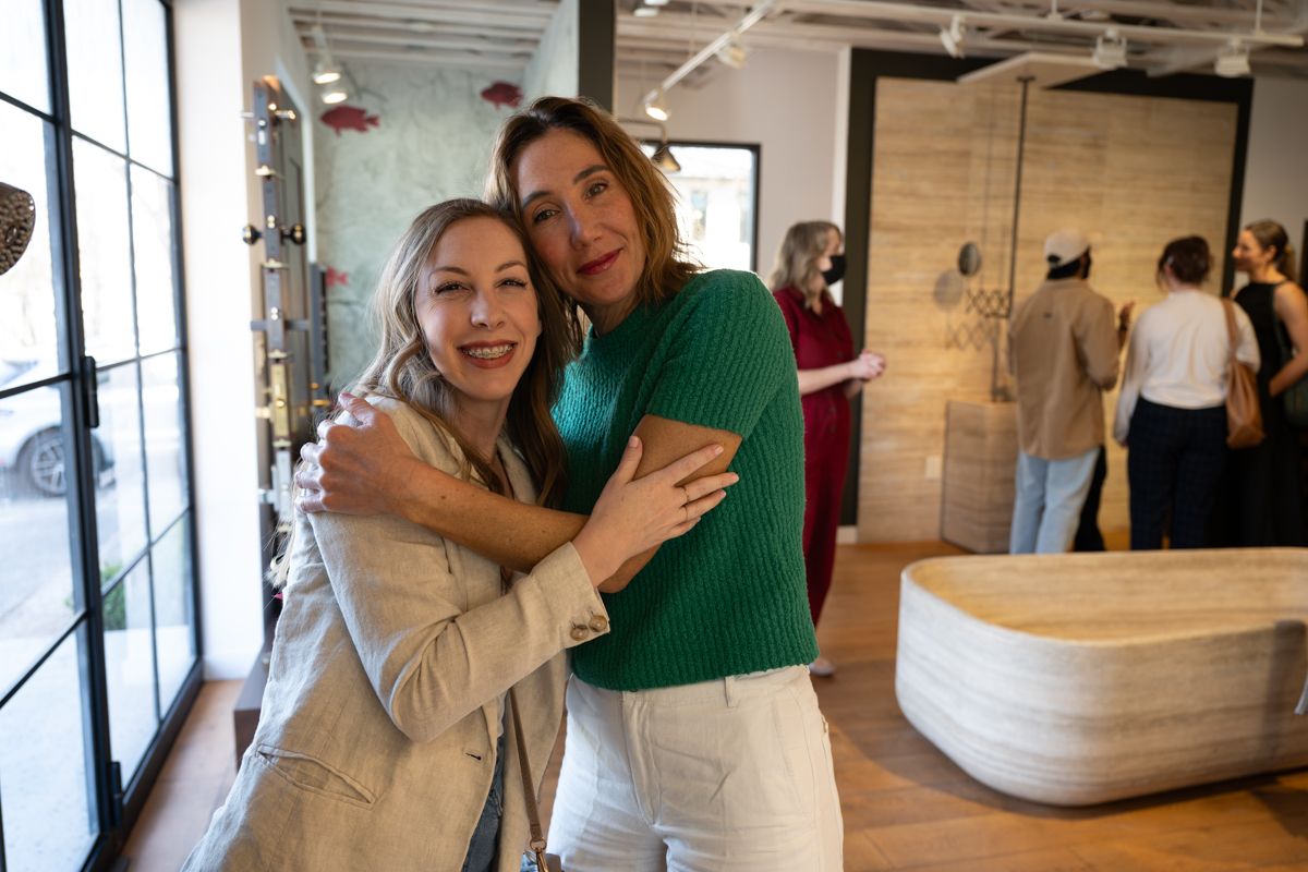 People in white aprons and green shirts work together in a bright, modern kitchen setting.