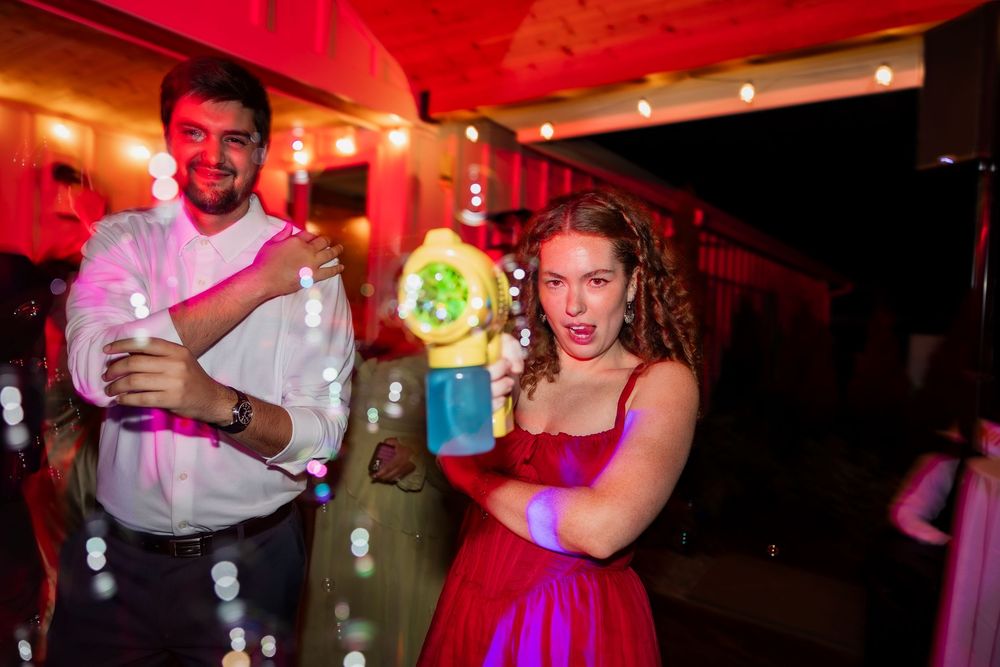 People dancing and socializing at a vibrant party with red lighting and festive atmosphere.
