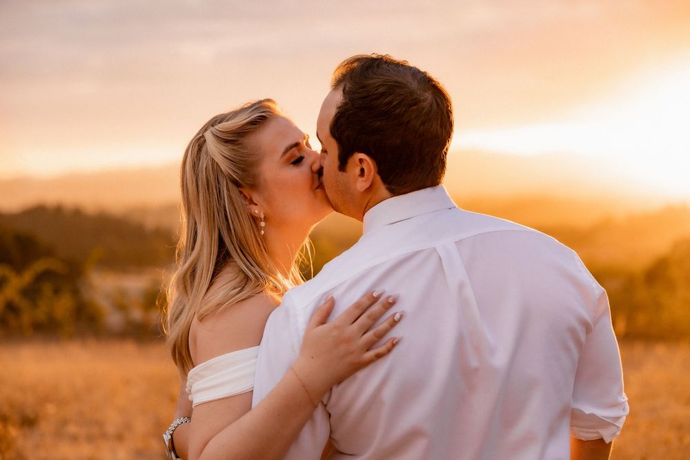 Romantic couple embraces during golden hour sunset in a scenic outdoor setting with warm glowing light.