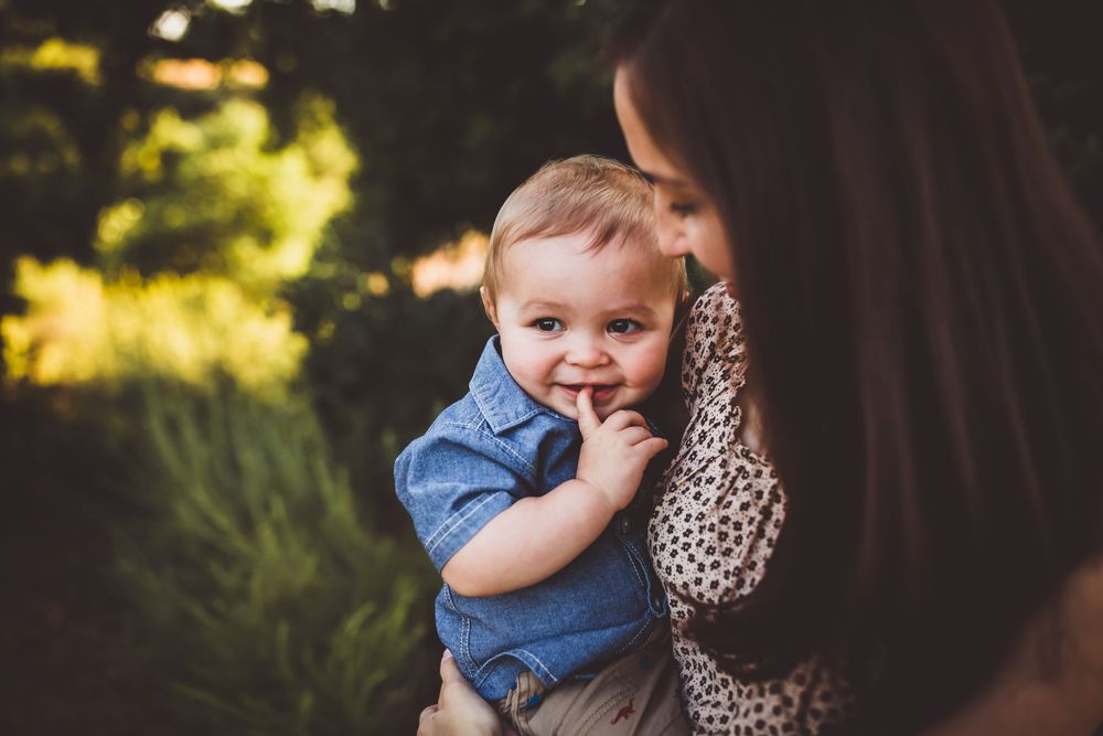 Sweet candid moment between parent and child sitting together outdoors at sunset.
