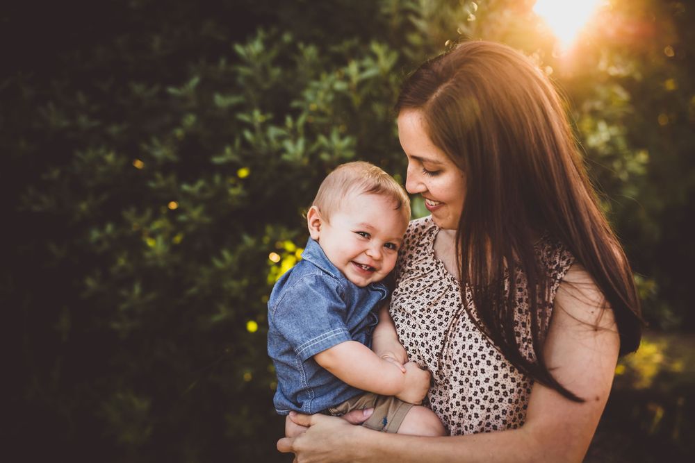 A tender moment between parent and child captured in golden sunlight amidst lush greenery.