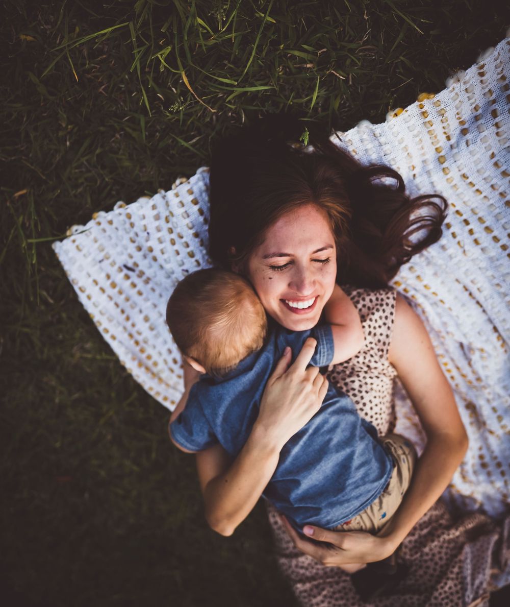 A couple relaxes together on a white knit blanket during an intimate outdoor photoshoot.