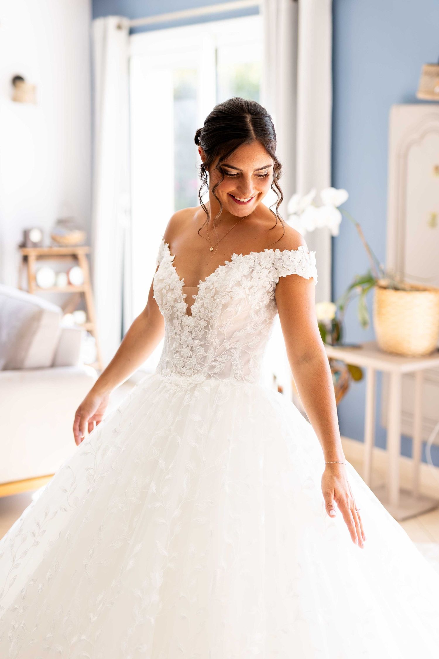 Belle robe de mariée blanche avec corsage en dentelle délicate et jupe en tulle photographiée dans une pièce lumineuse et ensoleillée.