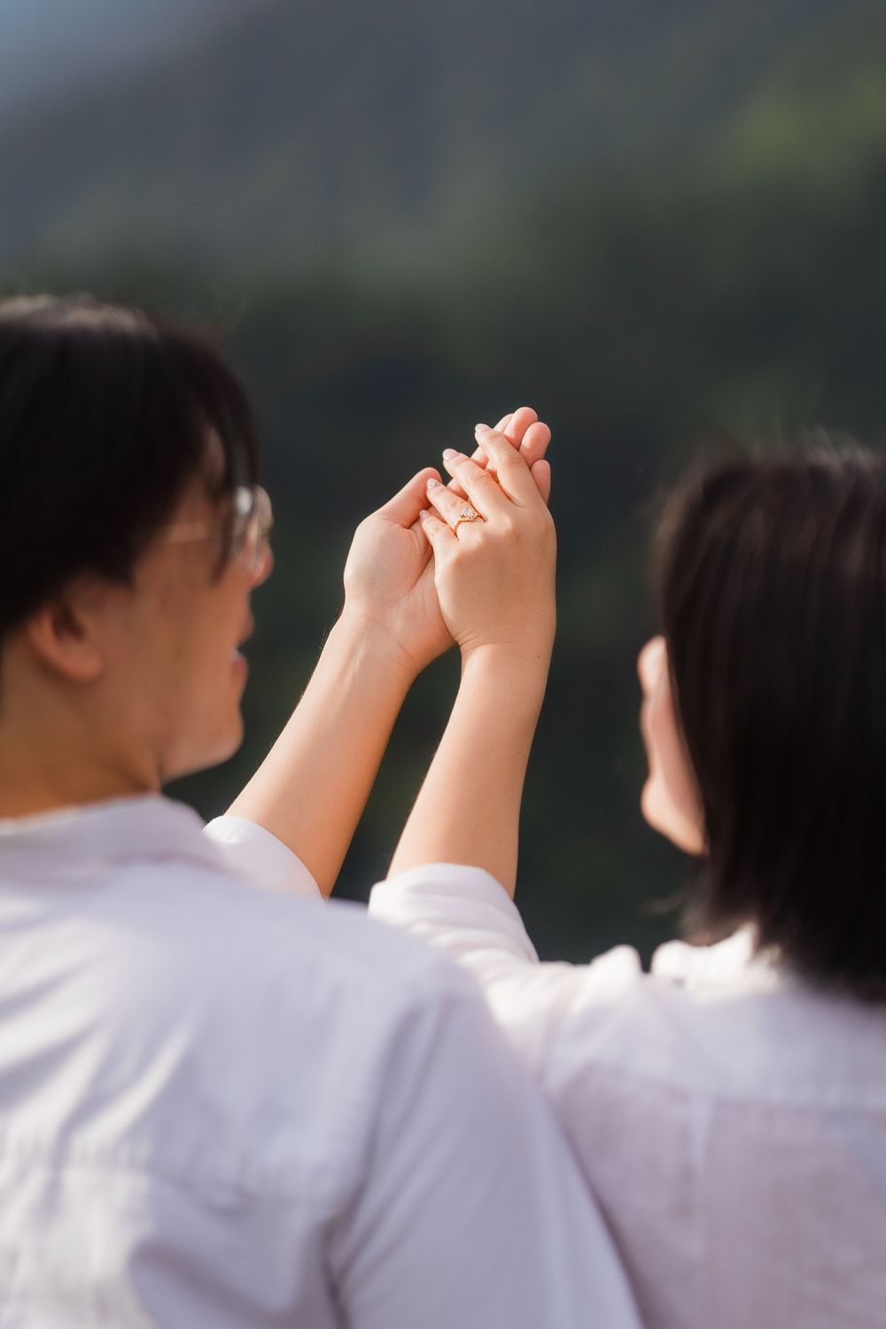 Students in white uniforms hold hands together in a line during an outdoor ceremony or gathering.
