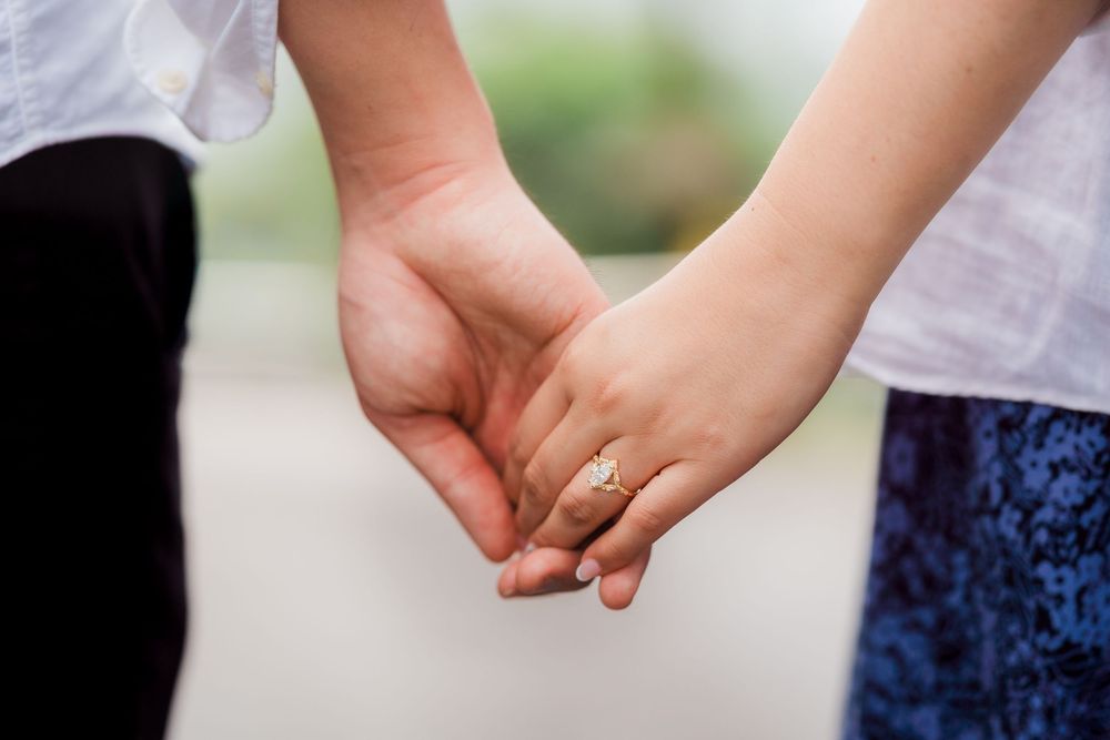Close-up of hands holding each other against a blurred outdoor background.