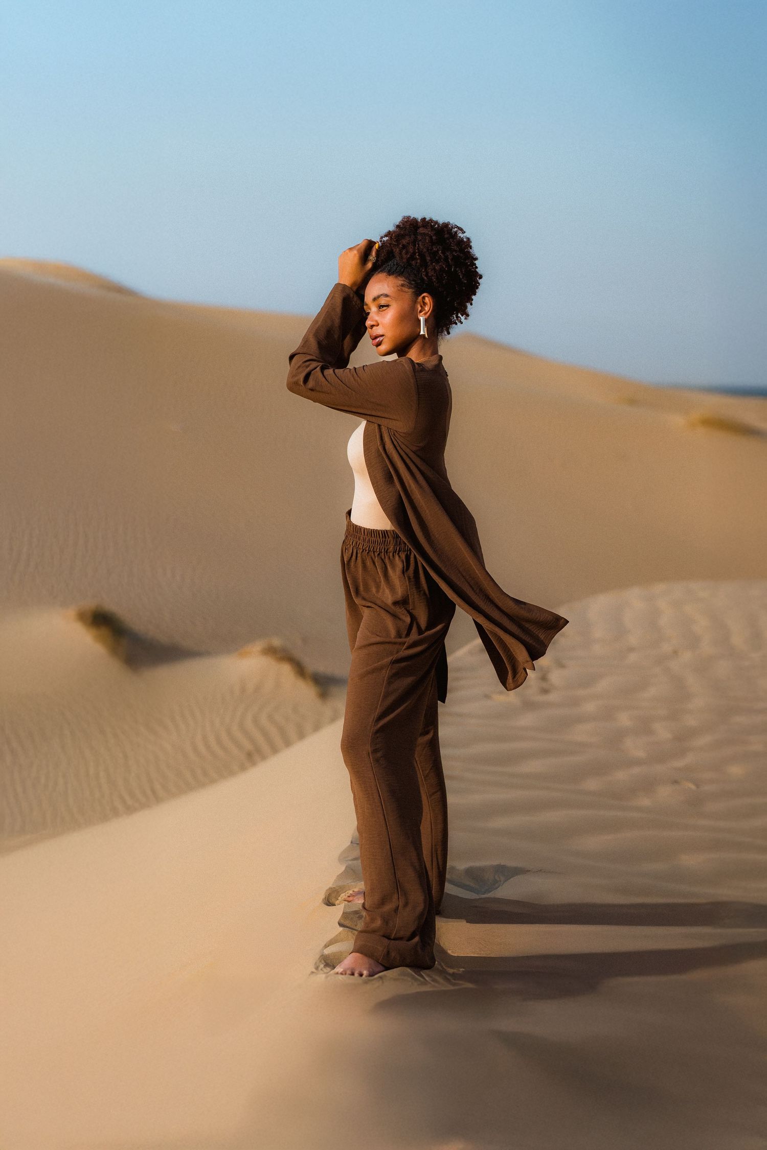 Desert fashion photography in Dubai with flowing brown dress and blue sky