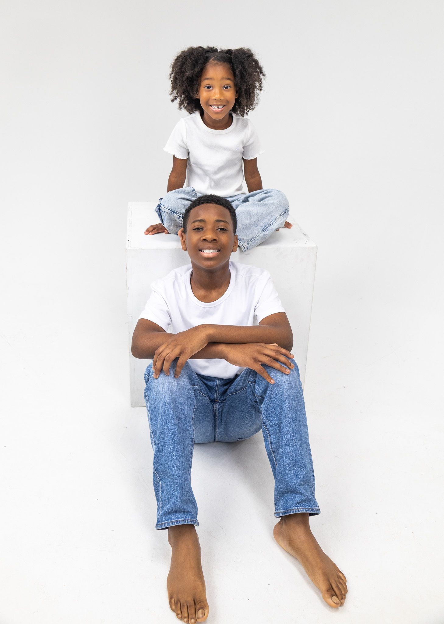 A young person in a white t-shirt and jeans sits casually on a white background in three similar poses.