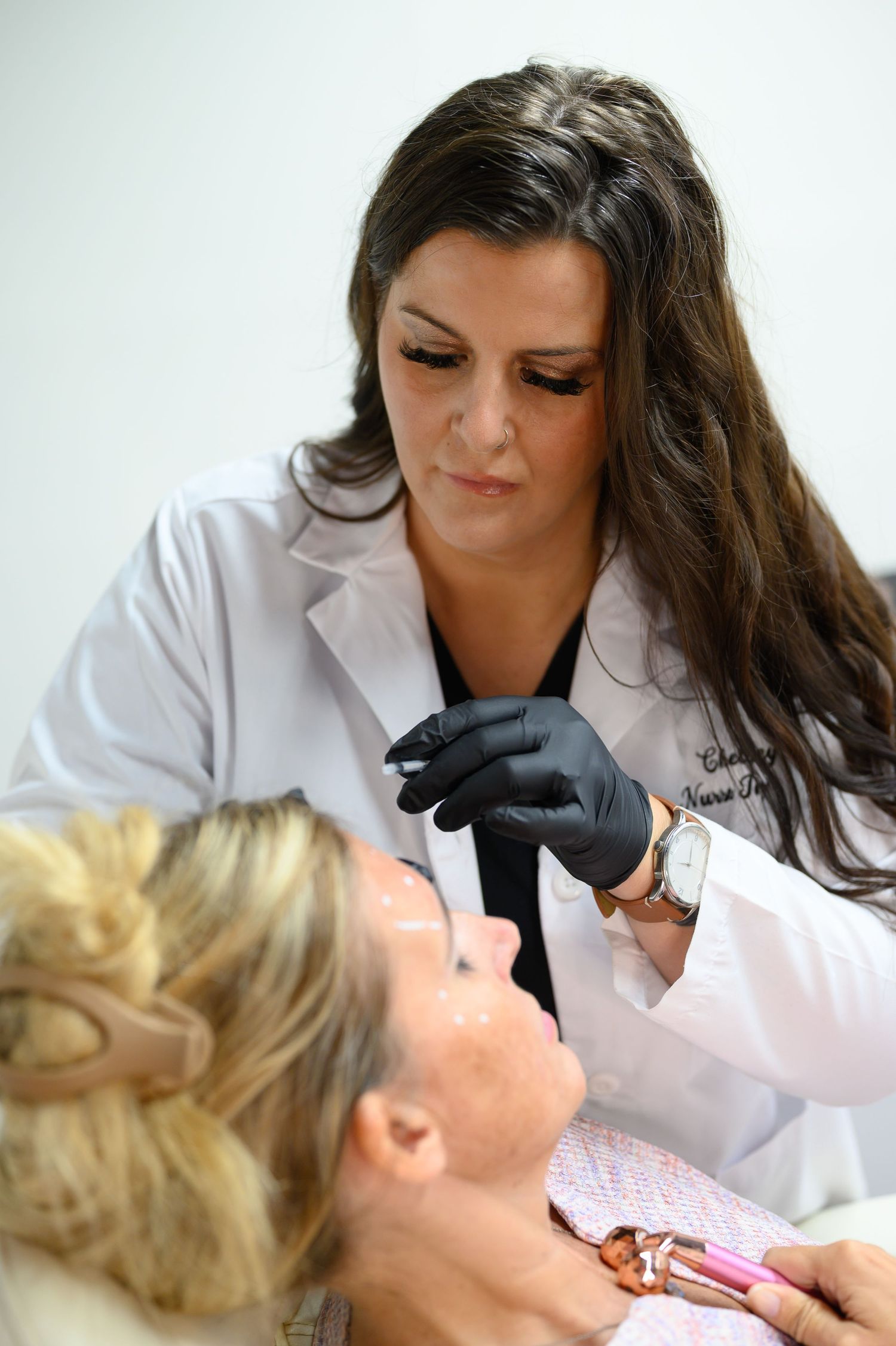 A dental professional in white coat performs a dental examination on a patient in a clinical setting.
