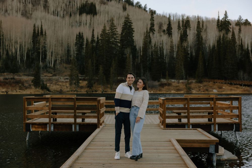 A scenic outdoor wedding ceremony setup with wooden benches and mountain views at sunset in a rustic forest setting.