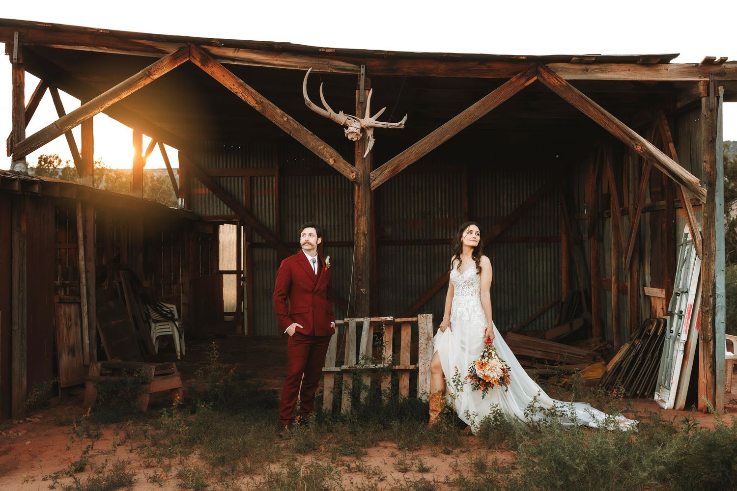 Ghost Ranch Bride and groom standing apart in rustic barn doorway at golden hour sunset.