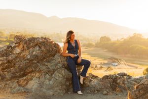 Person in denim outfit poses confidently on rocky outcrop during sunset.