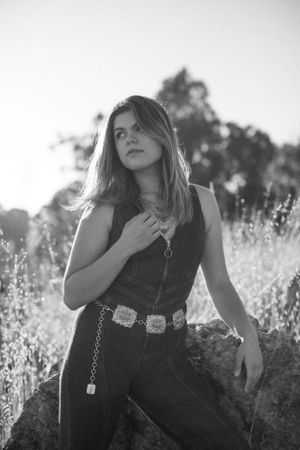 Black and white portrait of person in denim against wild grasses.